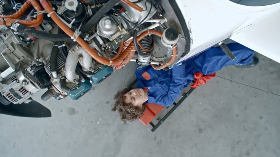 Technician inspecting a piston aircraft with the cowl open